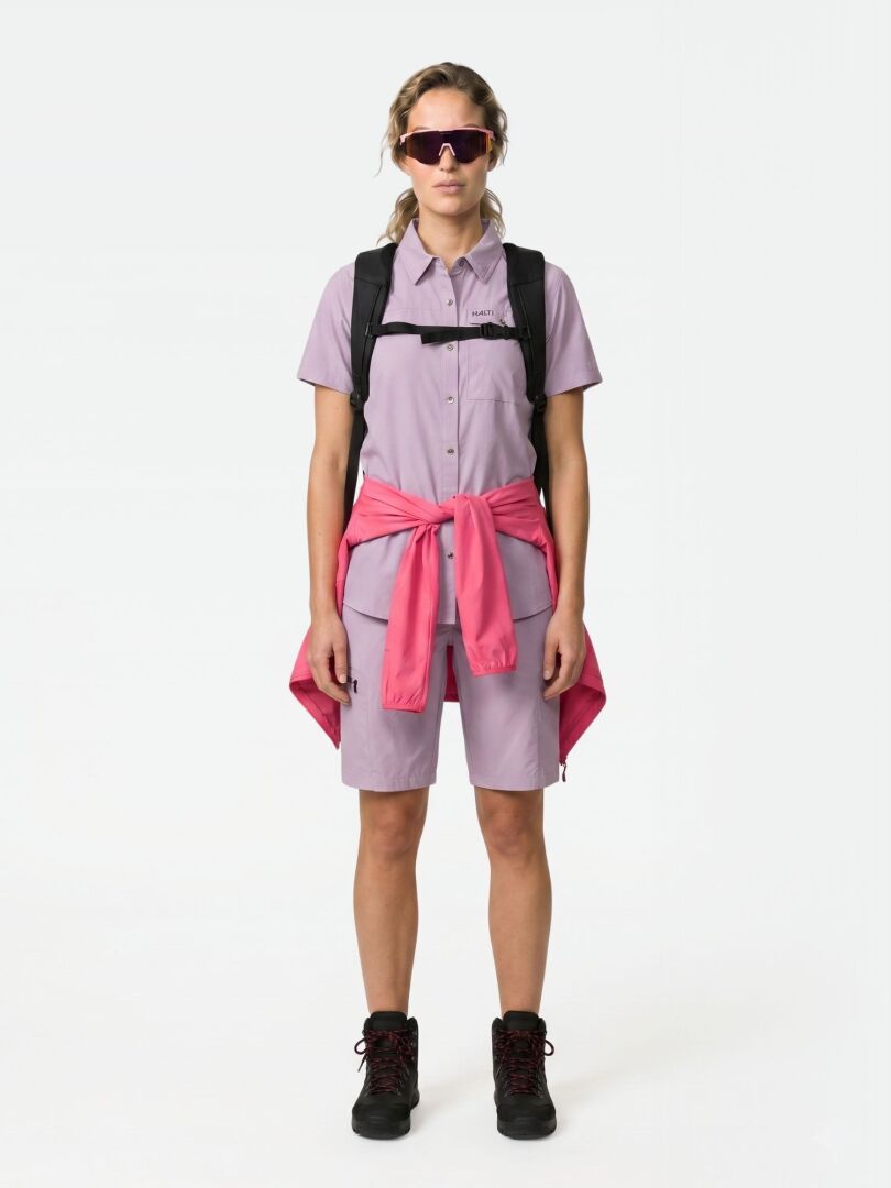 Wearing a Halti Samoy Trekking Shirt Women's, shorts, pink jacket at waist, backpack, sunglasses, and black boots.