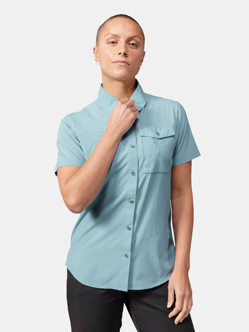 A woman wearing the Halti Samoy Trekking Shirt in light blue with a front pocket, against a white background.