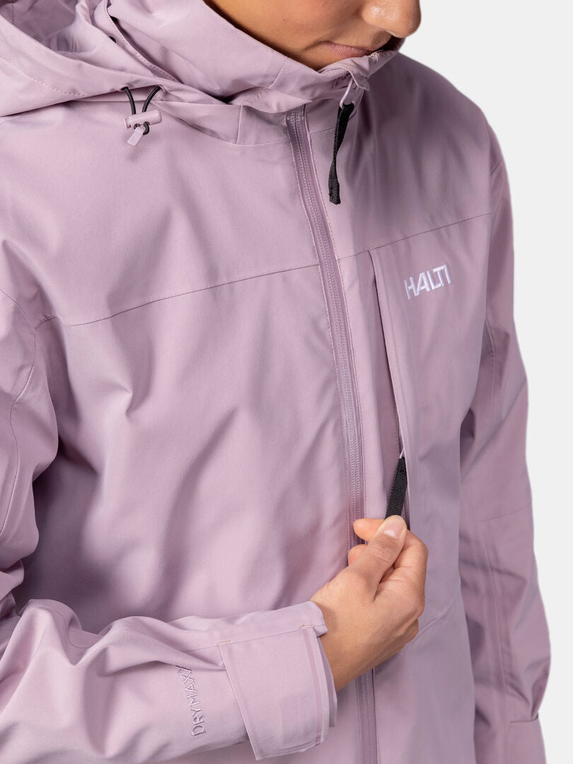 Woman wearing a light purple Halti Valaja DX Parka Jacket, unzipping the chest pocket; only lower face and upper torso visible.