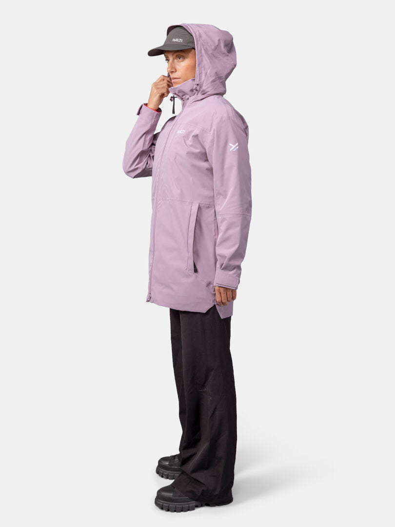 Woman in a light purple Halti Valaja DX Parka Jacket, black pants, and shoes, standing sideways against a plain background.