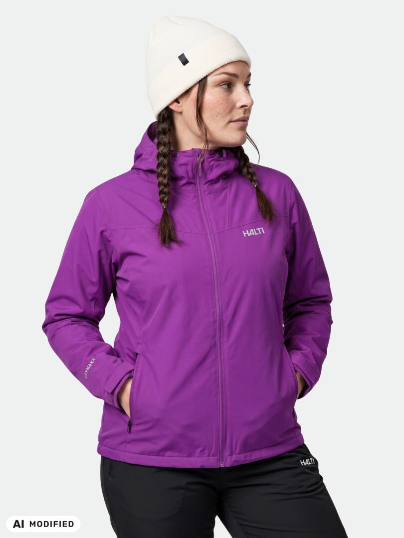 Woman in white beanie and Halti Finholma X-stretch Jacket stands hands-in-pockets, looking to the side.