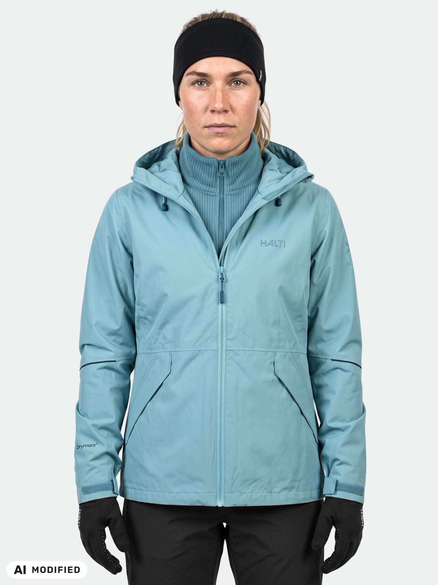 Woman facing forward in Halti Loito 3in1 DX Jacket (light blue), black gloves, and a headband against plain backdrop.
