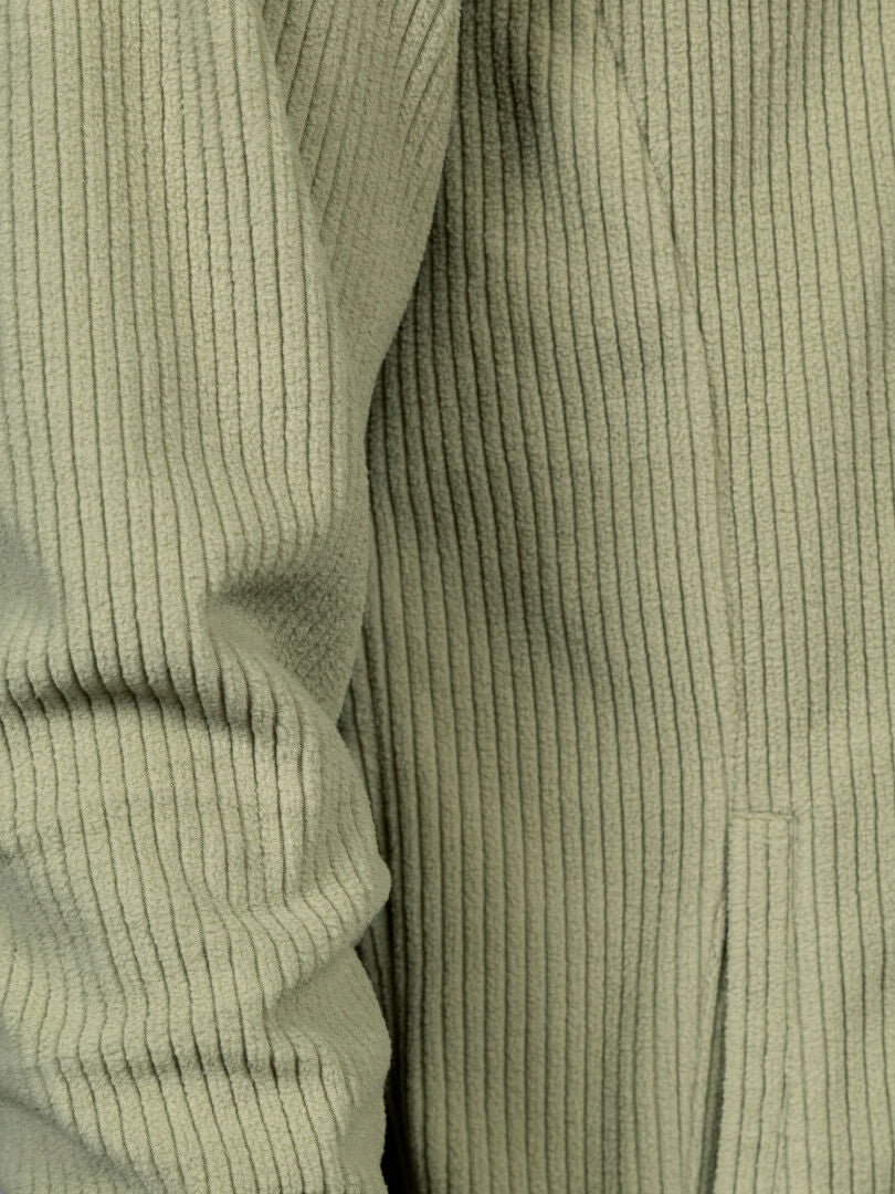 Close-up of Halti Loito 3-in-1 DX men’s jacket in light green corduroy, showing ribbed sleeve and side pocket seam.