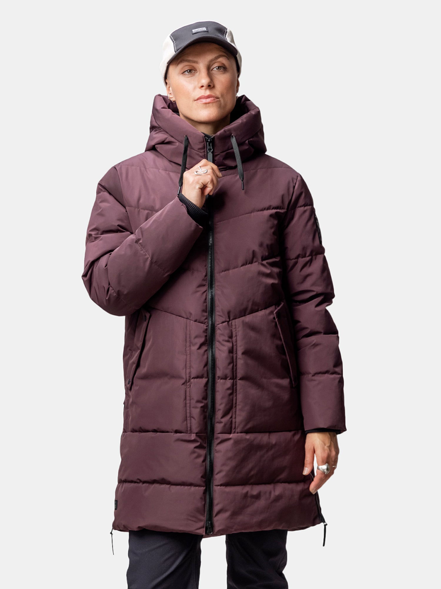 Person wearing Halti Linjat Parka Jacket Women's in maroon, black pants, and light gray cap against a plain background.