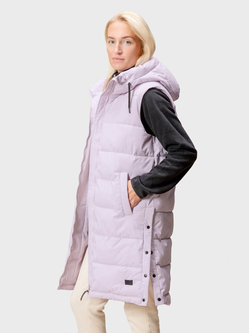 A woman wears the Halti Penger Puffer Vest in light purple with a hood, standing against a plain light gray background.