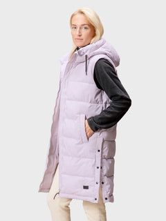 A woman wears the Halti Penger Puffer Vest in light purple with a hood, standing against a plain light gray background.