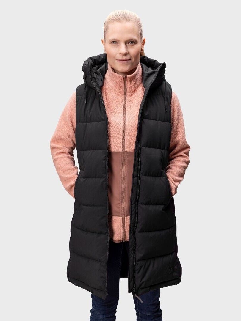A woman faces forward, wearing the Halti Penger Puffer Vest over a pink zip-up jacket and dark pants.