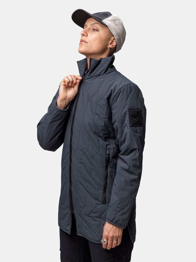 Woman wearing Halti Synkas 3in1 DrymaxX Parka, dark gray, with a gray cap, zipping up against a plain background.