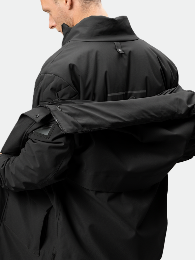 A man in a Halti Synkas 3in1 DrymaxX Parka is seen from behind, adjusting or removing another black jacket.
