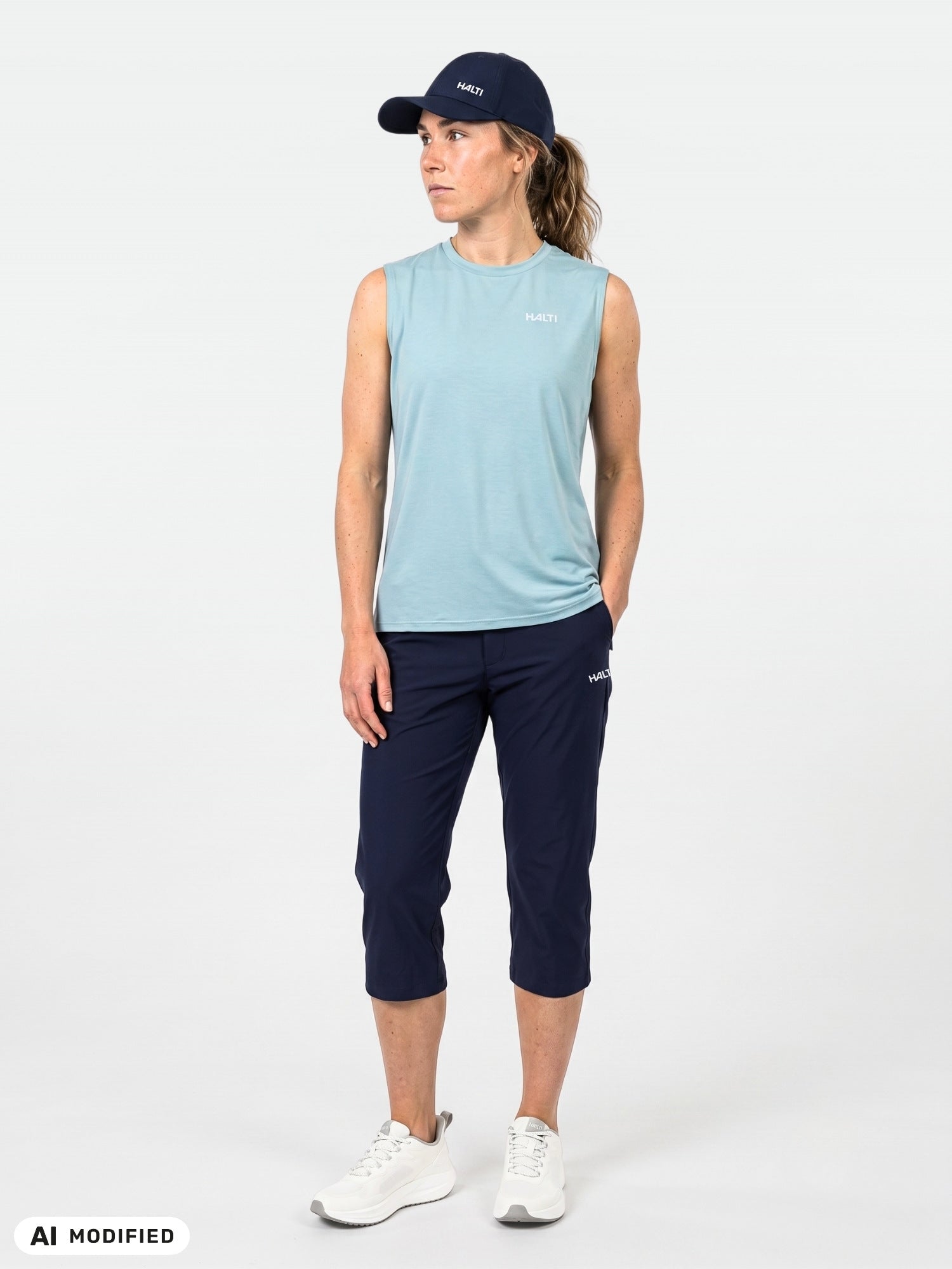Person wears a blue sleeveless shirt, Halti Drive X-stretch Capri Pants with UPF 50+, and a navy cap.