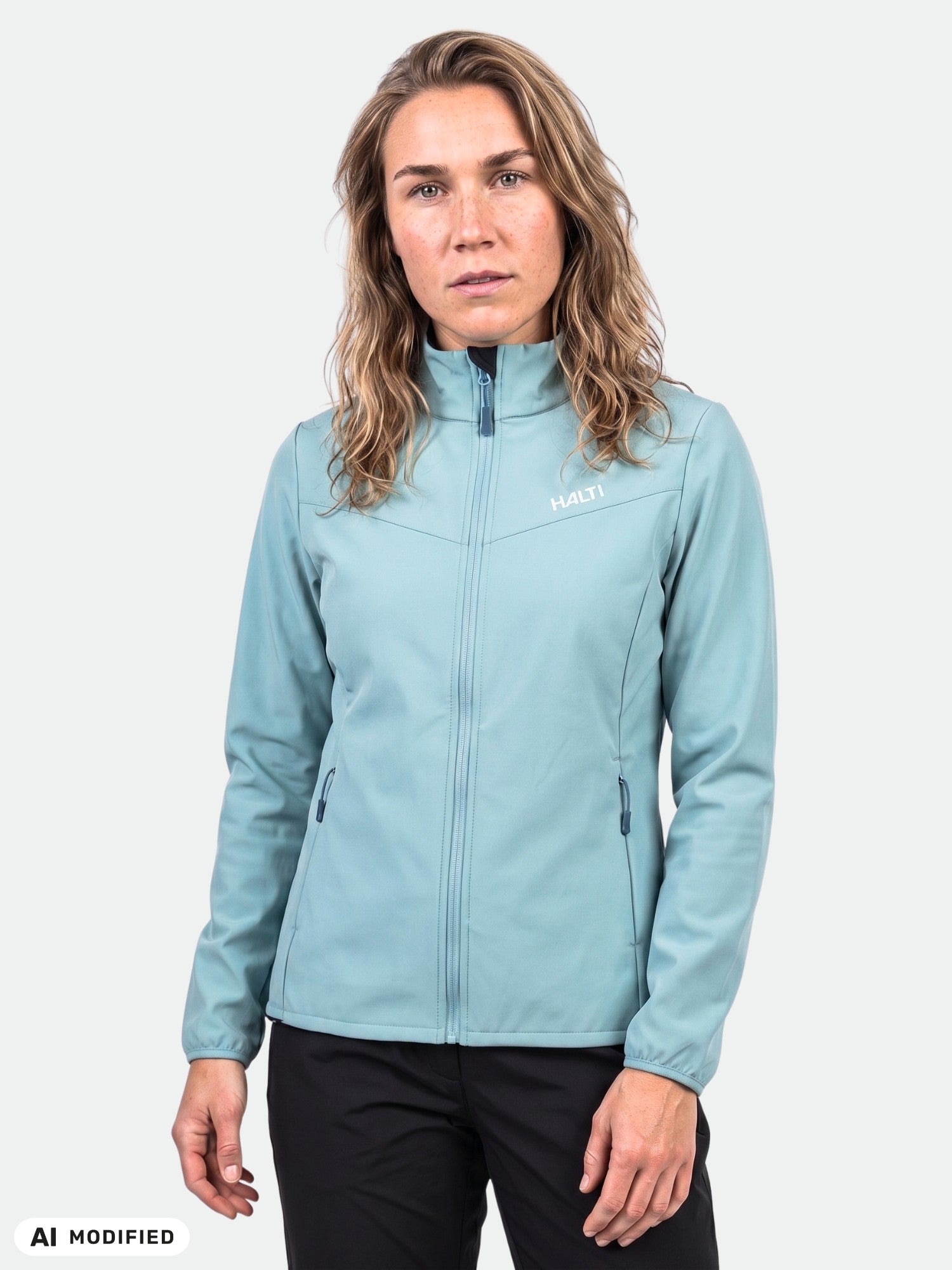 A woman wears the Halti Wedge Softshell Jacket and black pants, standing against a plain white background.
