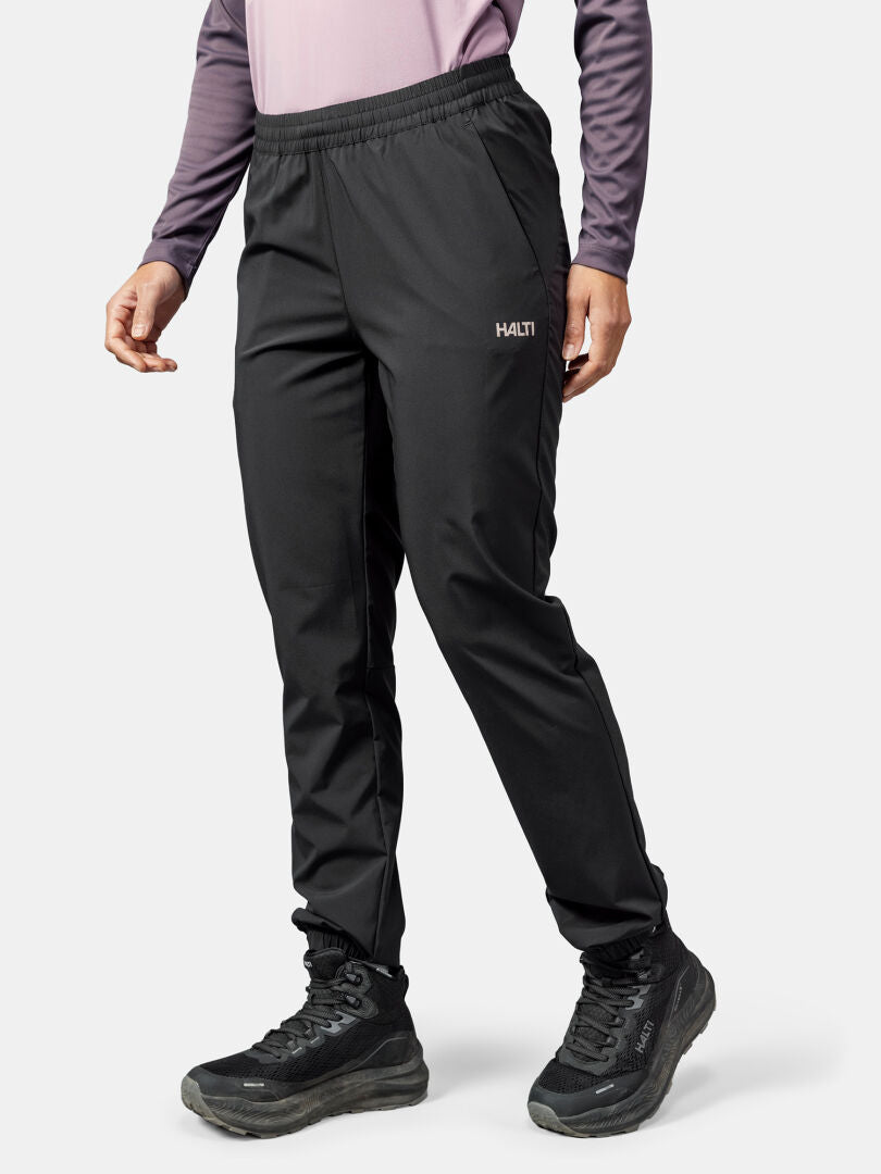 A person wears Halti Grets Jogger Pants for women, a purple long-sleeve top, and black sneakers against a plain background.