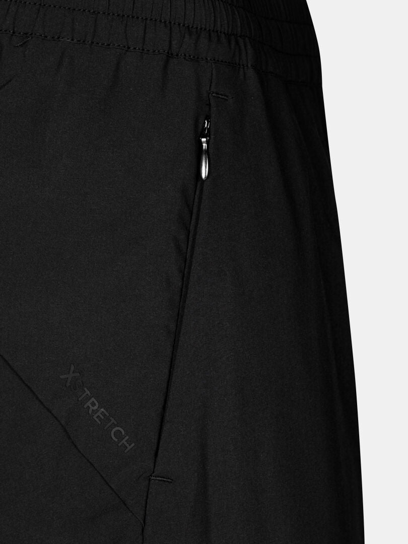 Close-up of Halti Grets Jogger Pants Women's in black, with a zippered pocket and XTRETECH printed on the fabric.