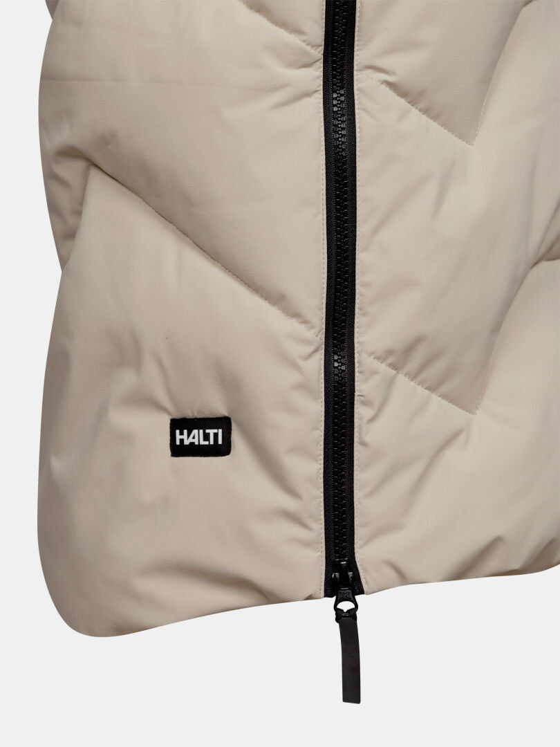 Close-up of Halti’s Brahe Puffer Long Winter Jacket for women, beige with black zipper and front logo patch.