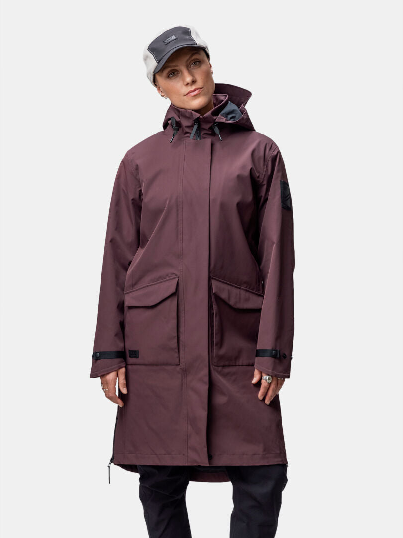 Wearing a Halti Tokoi II DX Parka Jacket Womens in maroon, black pants, and a two-tone cap against a plain background.