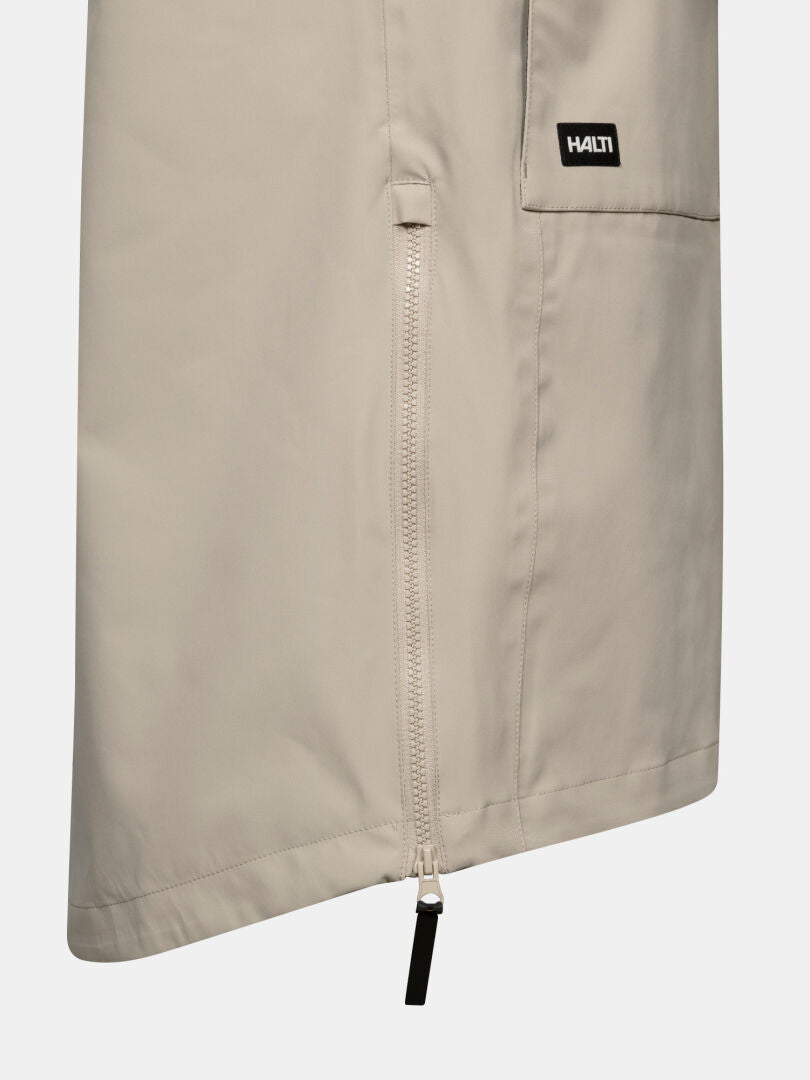 Close-up of a beige Tokoi II DX Parka by Halti, featuring a vertical zipper and a black patch with Halti in white.
