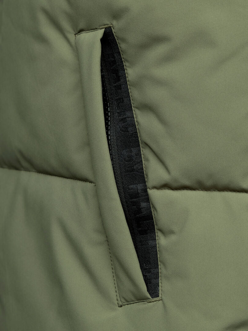 Close-up of Halti's Penger Classic Puffer Vest Men's in olive green, showing pocket texture, stitching, and black zipper.