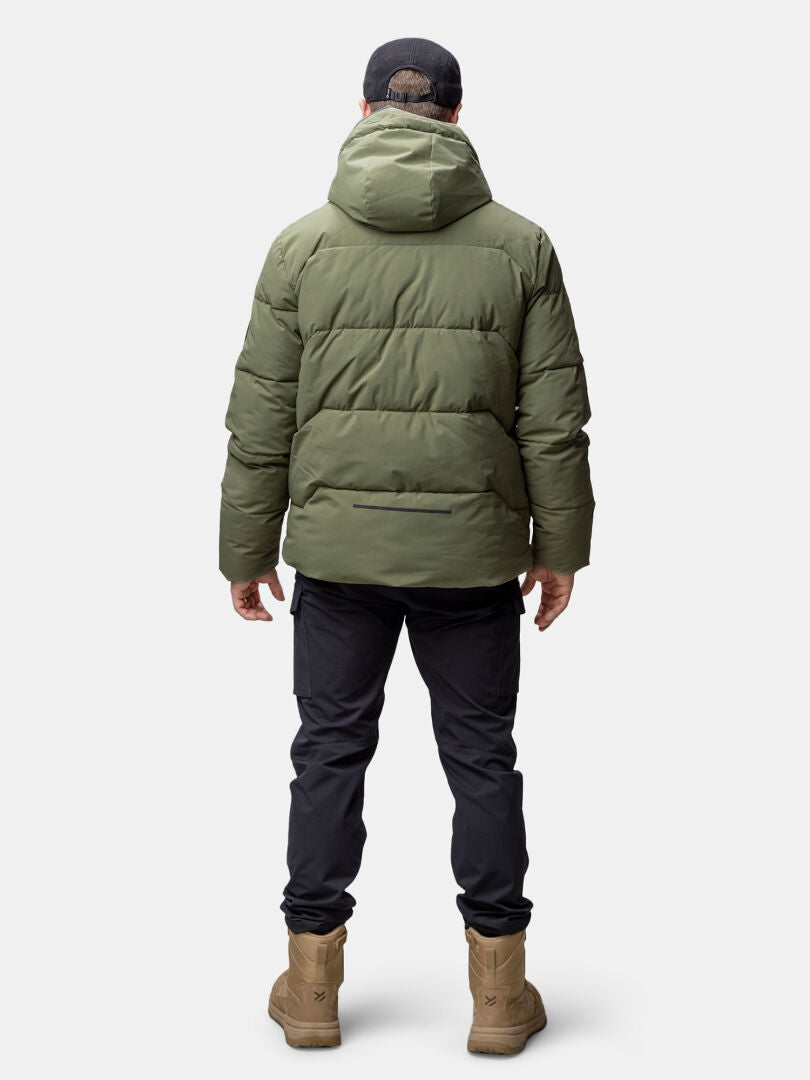 A man in a Halti Brahe Puffer Winter Jacket, black pants, tan boots, and black cap, shown from the back.