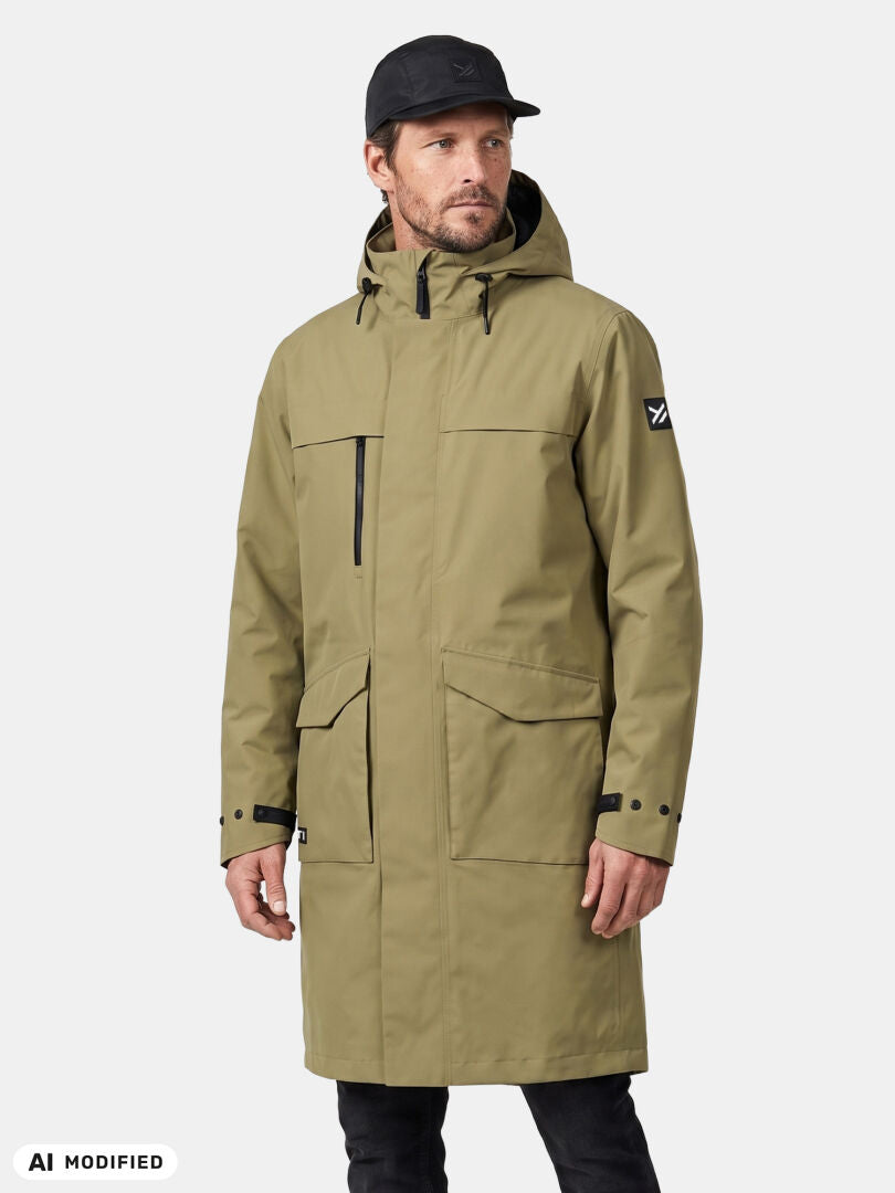Man in Halti Tokoi II DX Parka Jacket, long tan DrymaxX with hood and pockets, wearing black cap, plain background.