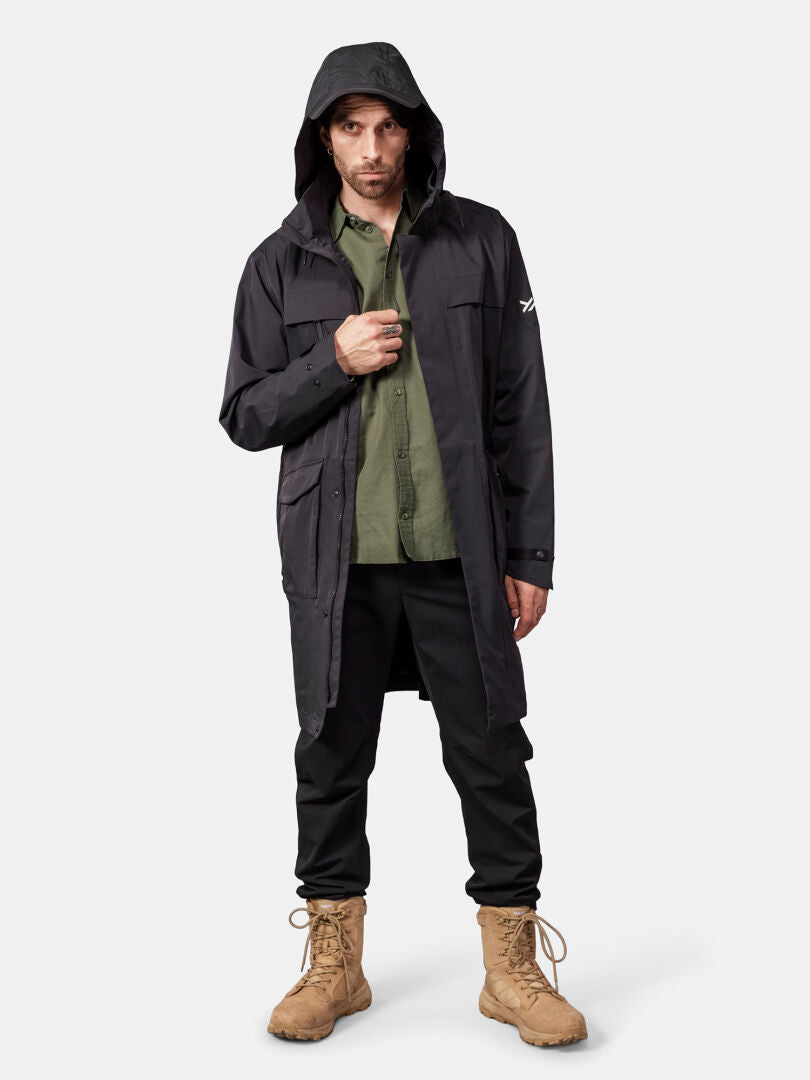 Man in Halti Tokoi II DX Parka, green shirt, black pants, tan boots, standing against a plain background.