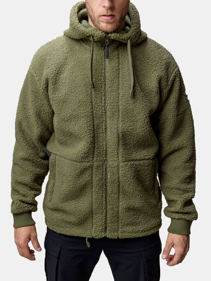 A man wears the Halti Lykky Fleece Jacket (olive green, hoodie-style, front pockets) with black pants.