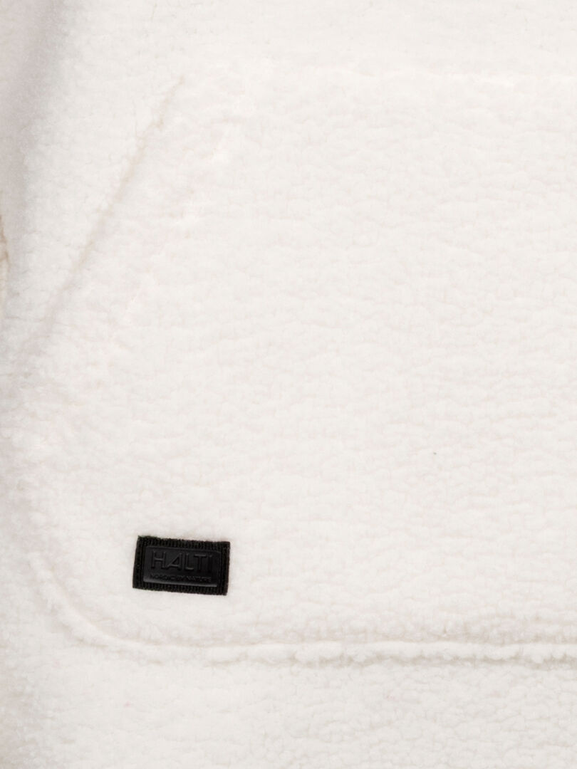 Close-up of a white textured recycled polyester pocket with black Halti tag on the Lykky Fleece Pullover Womens.