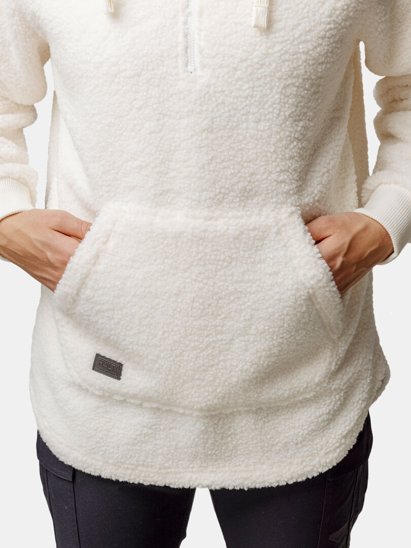 Woman wearing the Halti Lykky Fleece Pullover, a white recycled polyester top with a front kangaroo pocket.