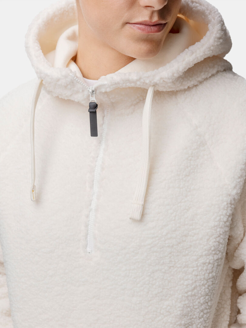 Model wears the Halti Lykky Fleece Pullover Womens, a cream hoodie with drawstrings and high collar, shown shoulders up.