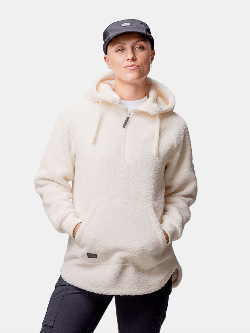 Person wearing a Halti Lykky Fleece Pullover Womens, dark pants, and a dark cap with hands in pockets.