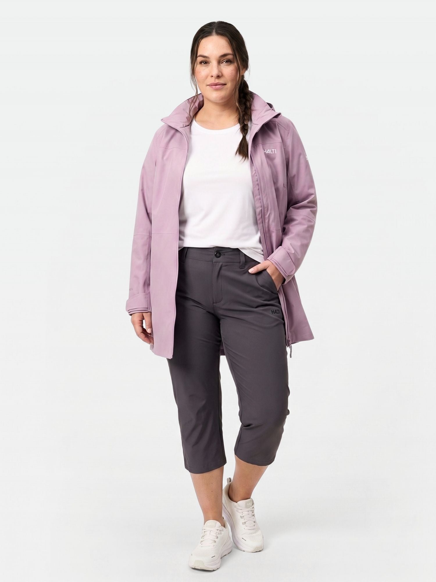 Woman in light purple jacket, white tee, Halti Drive X-stretch Plus capri pants, and white sneakers.