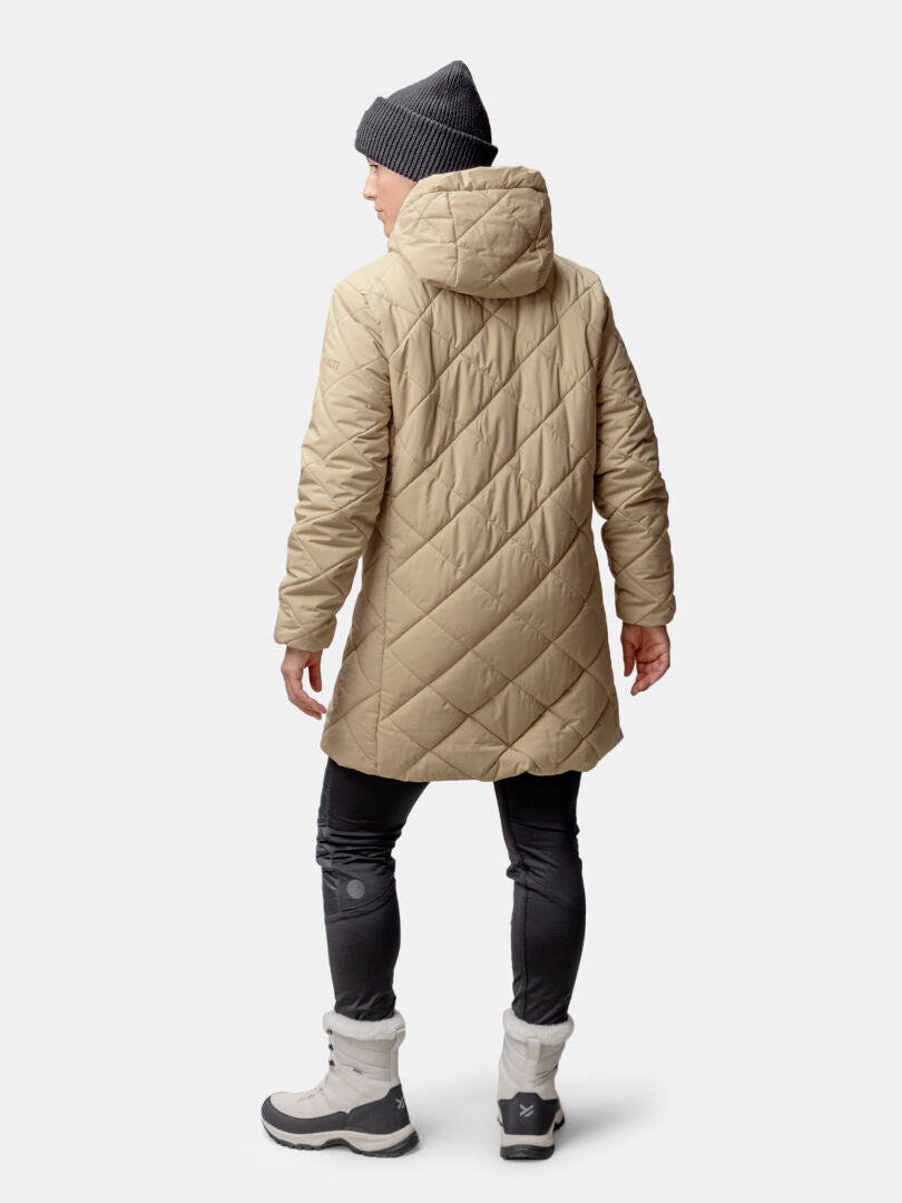 A person in a Halti Haapa Quilted Coat Jacket, dark pants, gray boots, and a gray beanie stands facing away.