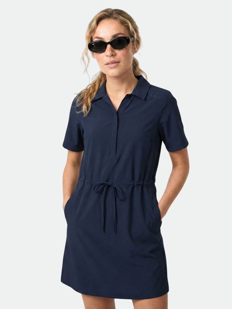 A woman wears the Halti Chipper II X-stretch Dress, featuring quick-dry stretch fabric and UPF 50+, hands in pockets.