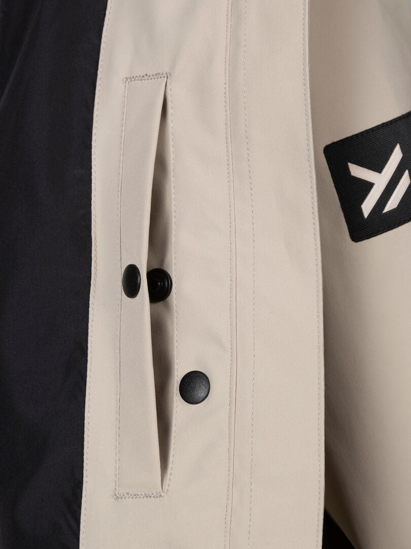 Close-up of the Halti Tokoi DX Jacket Women's pocket, featuring black buttons and a white geometric sleeve patch.