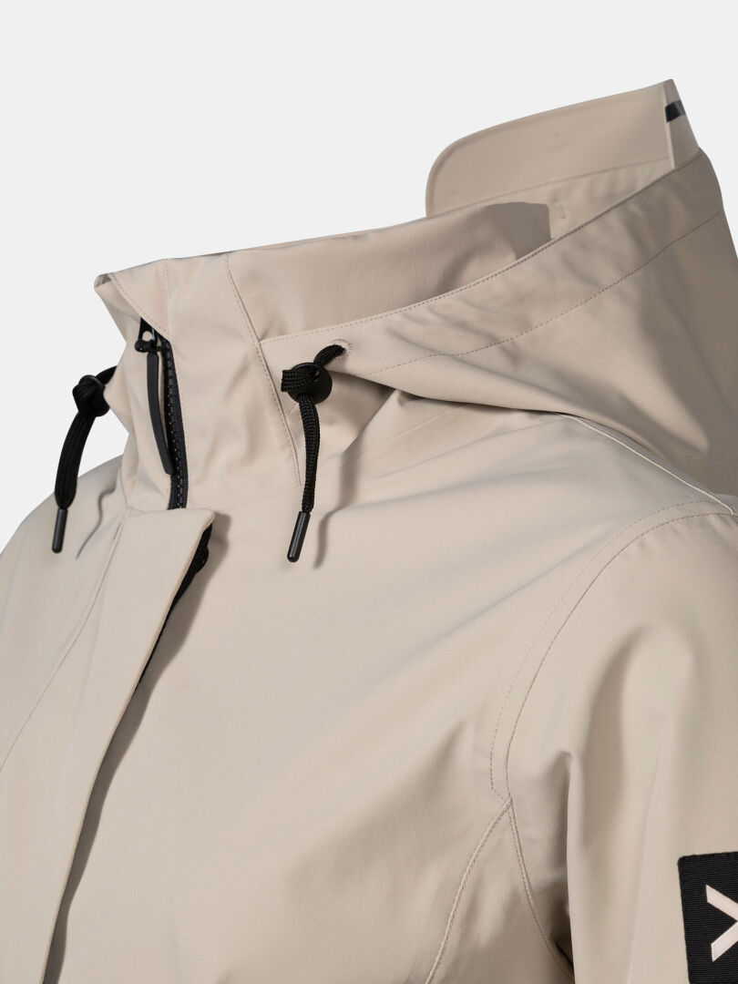 Close-up of Halti Tokoi DX Jacket Women's in beige with black drawstrings and patch, shown against a white background.