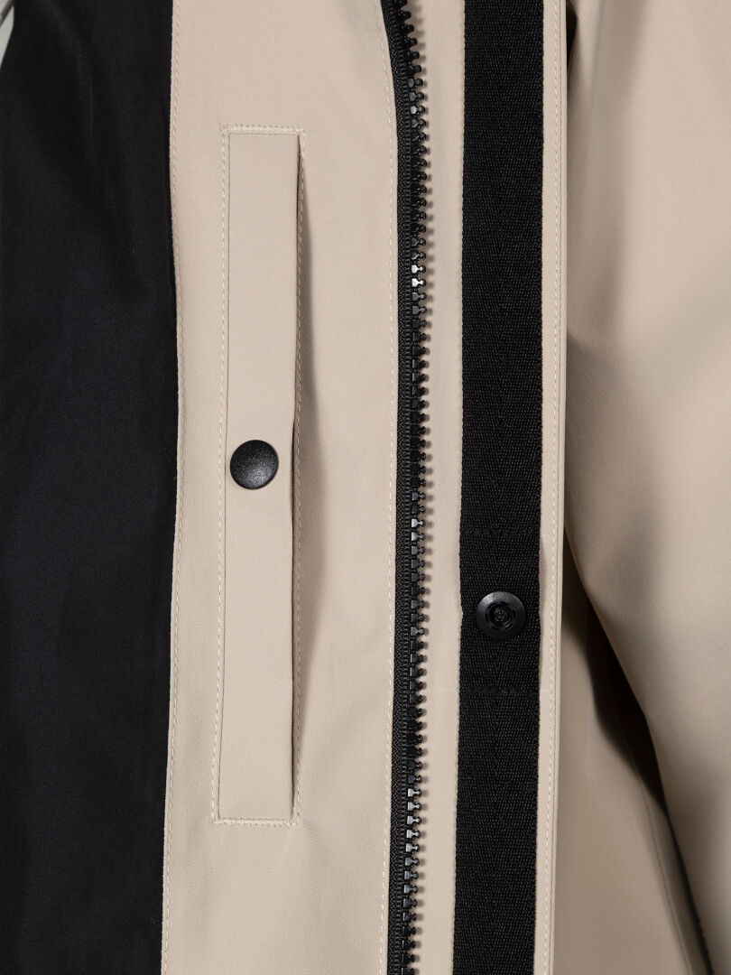 Close-up of Halti Tokoi DX Jacket Men's in beige, featuring a black zipper and snap button on the pocket flap.