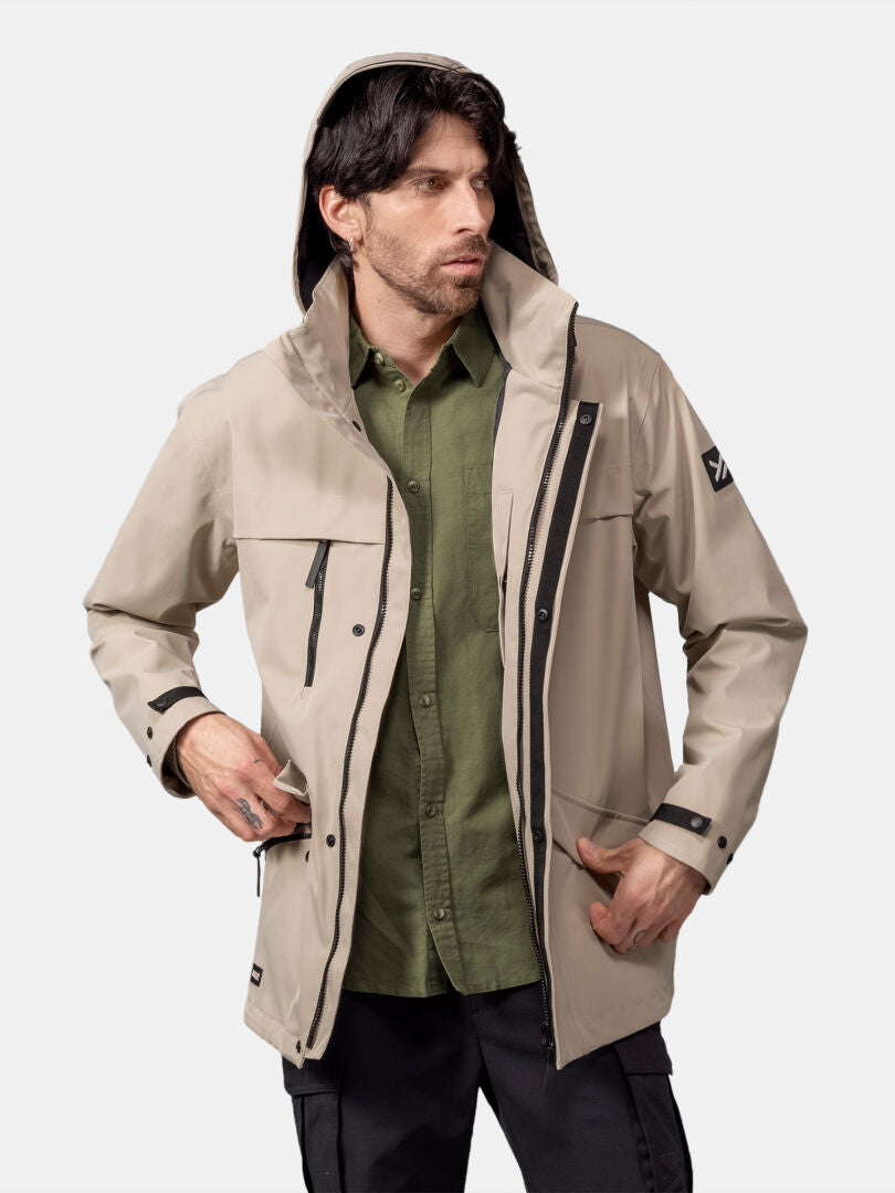A man wears the Halti Tokoi DX Jacket Men's in beige over a green shirt, with one hand in his pocket.