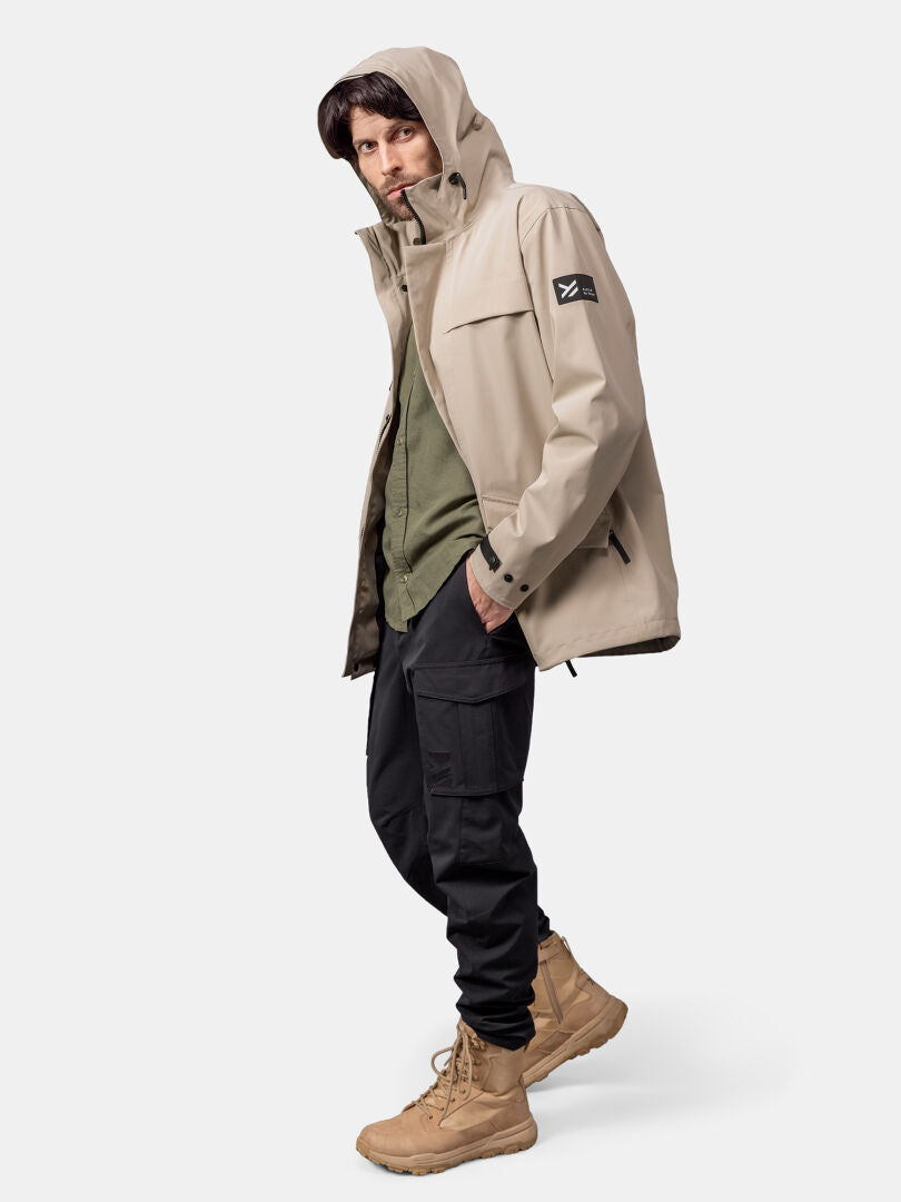 Wearing a Halti Tokoi DX Jacket, green shirt, black cargo pants, and tan boots, a man stands against a plain backdrop.