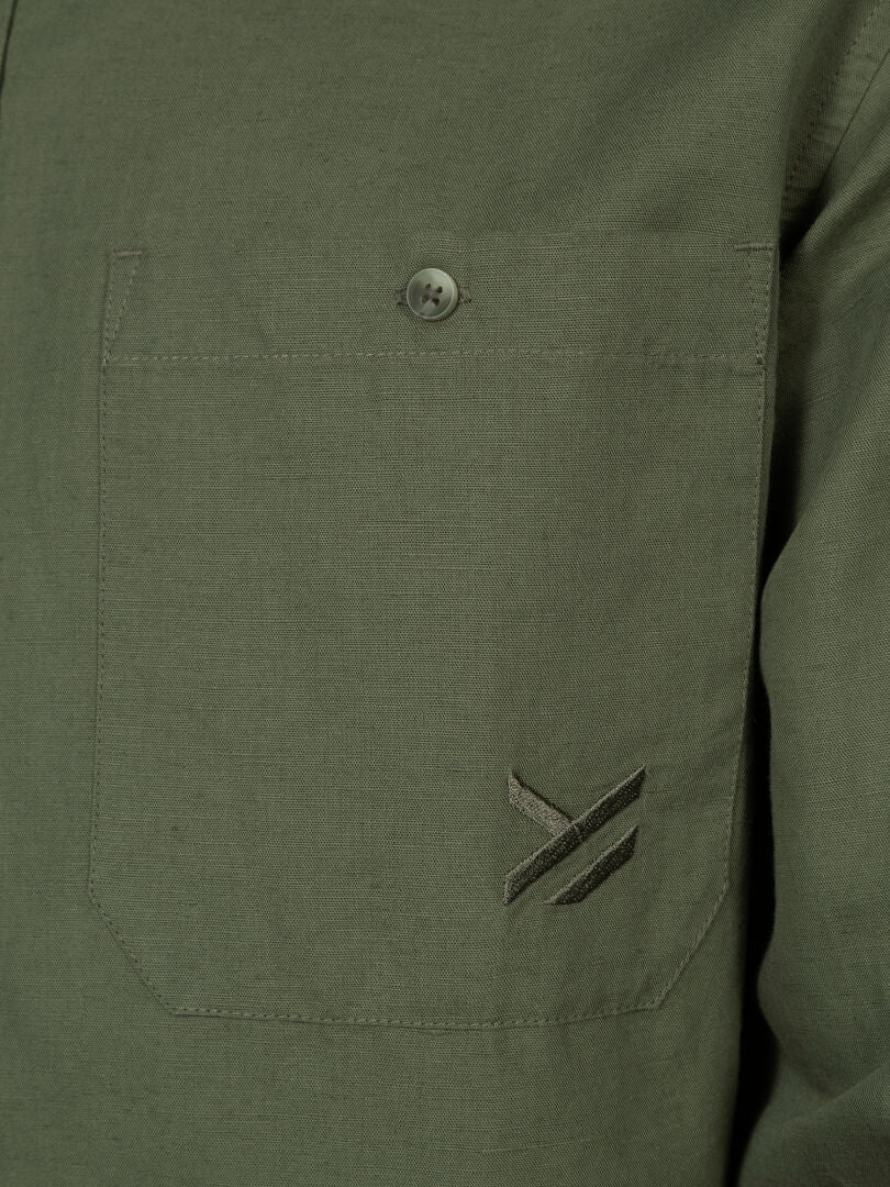 Close-up of Halti's Notsgi Longsleeve Shirt pocket, with button and small embroidered logo near the bottom edge.
