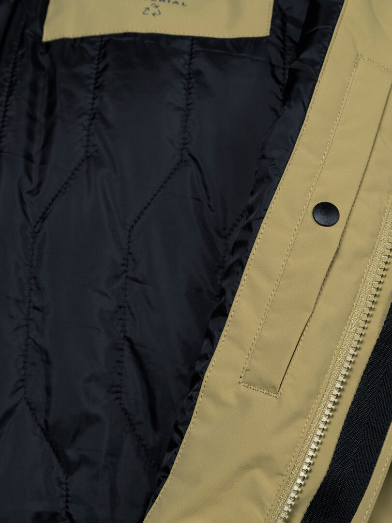 Close-up of Halti Kortteli DX Insulated Parka Men’s: black quilted lining, tan shell, zipper, and black snap button.