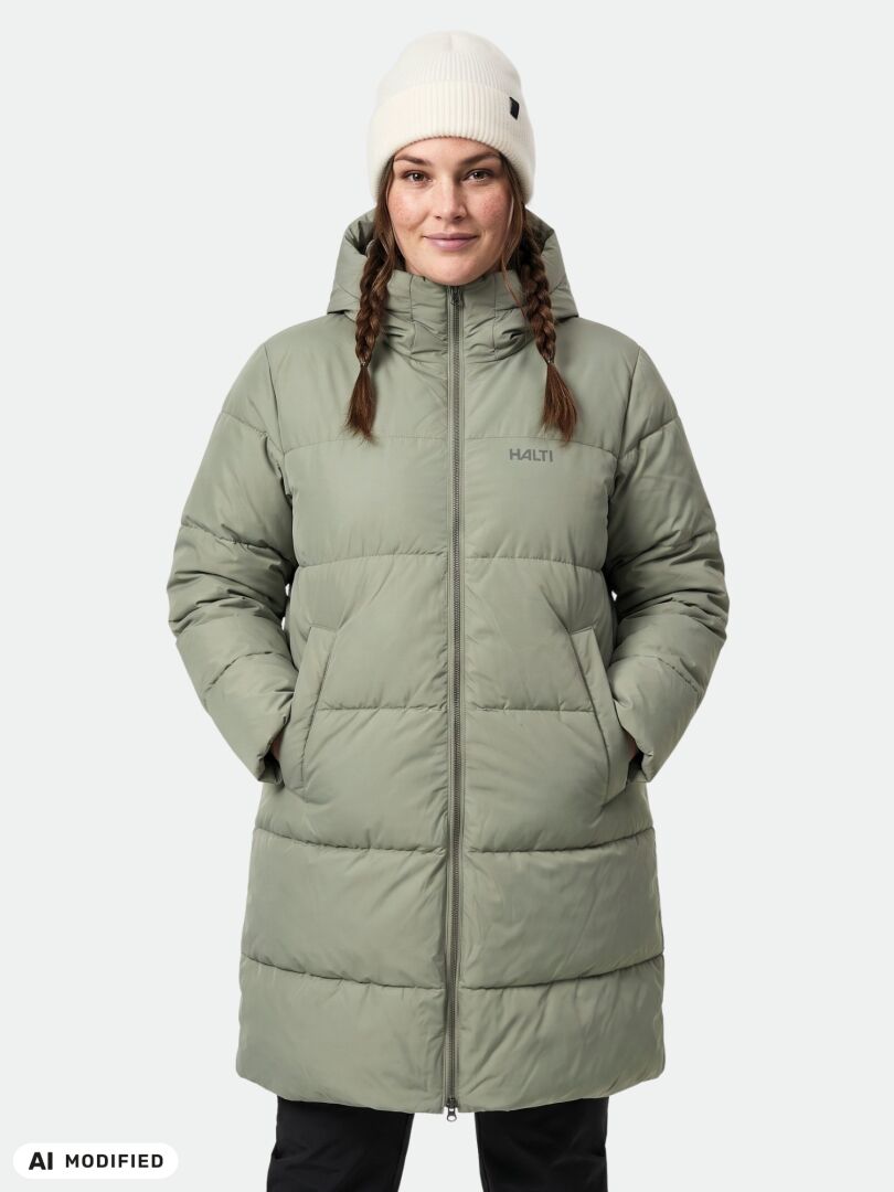 Woman wearing the Halti Sammal II Insulated Parka Jacket in light green with a hood and white beanie, hands in pockets.