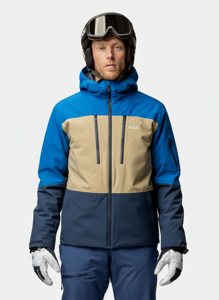 A man wears the Halti Melvik Dx Ski Jacket Men's in blue, beige, and navy, facing forward against a plain background.