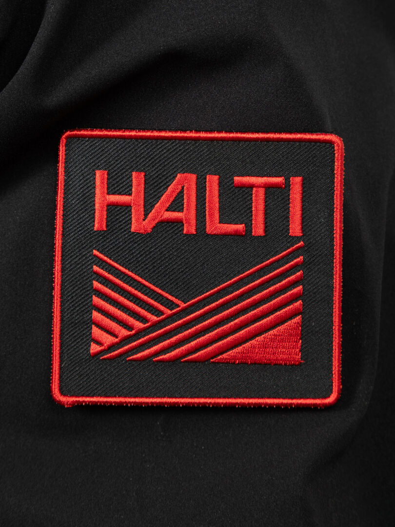 A black fabric patch for the Halti 1976 Down Parka with HALTI and a geometric red design, embroidered in red thread.
