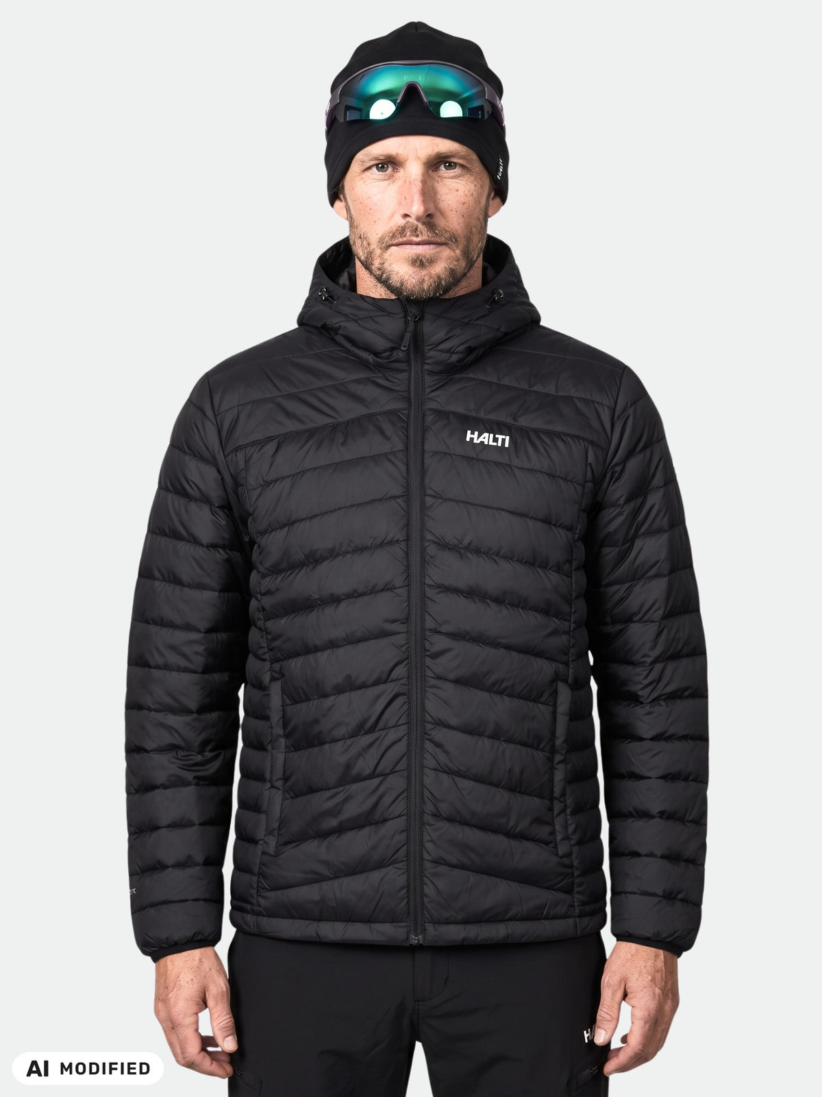 A man wearing a black, lightweight packable Halti Huippu Down Jacket Men’s with a hood.