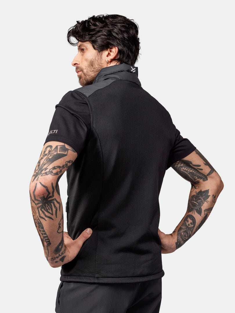 A tattooed man faces away from the camera, wearing the Halti Huippu Down Vest Men’s against a light background.
