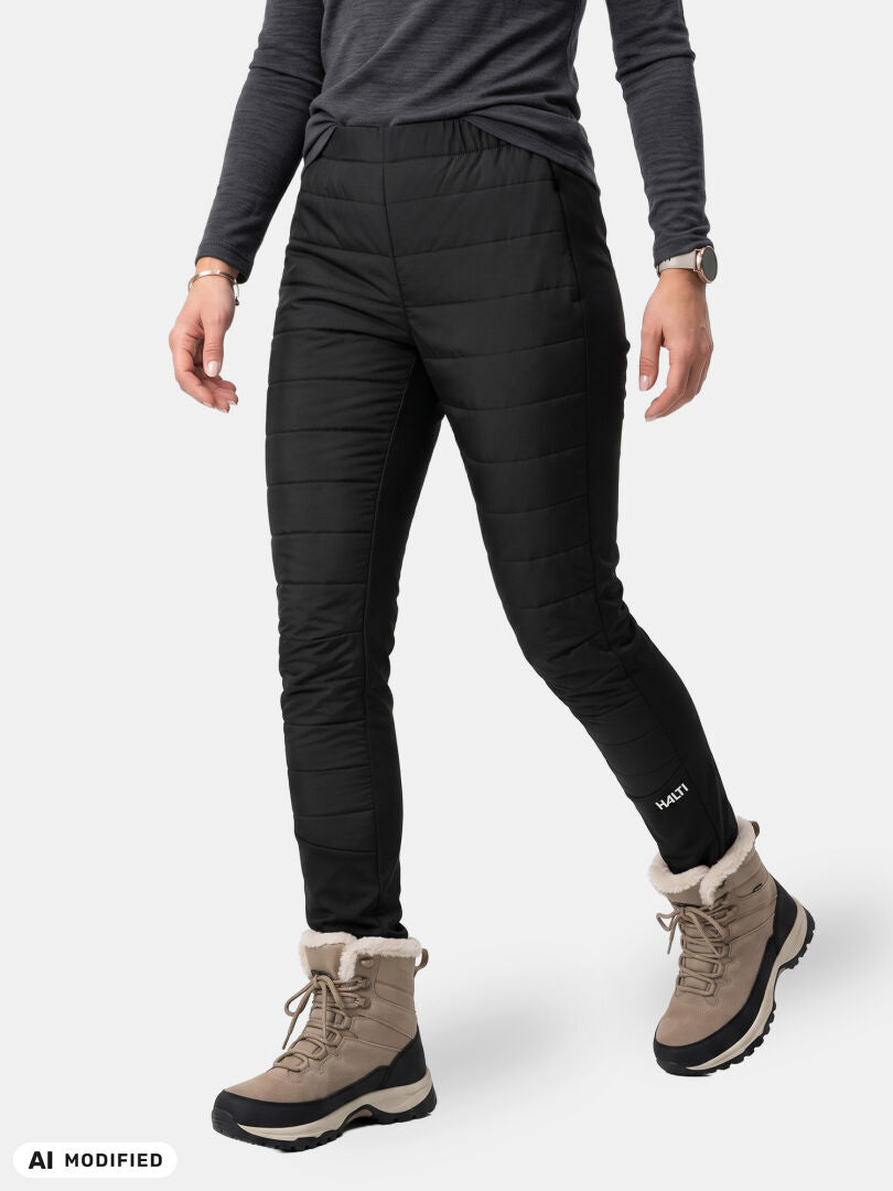 Woman in black Halti Valimo Hybrid Insulation Pants, gray long-sleeve top, watch, and tan fur-lined winter boots standing.