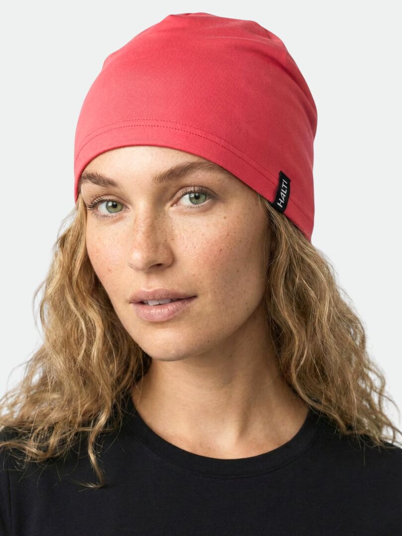 A person with wavy blond hair wears the Halti Loiva Beanie in pink and a black shirt, facing forward.