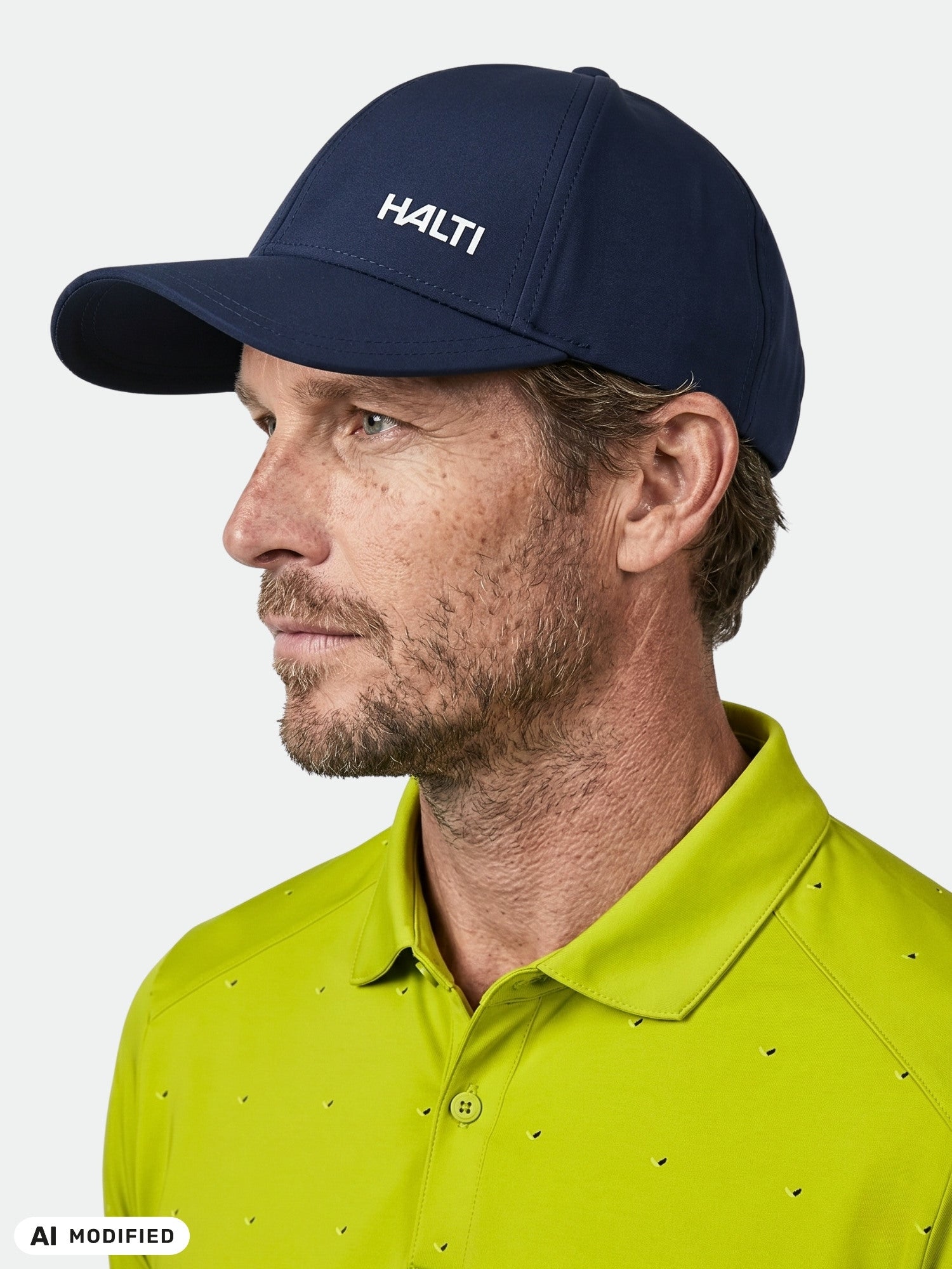 A man in a navy Halti Mattas Baseball Cap and lime green polo looks left against a plain background.