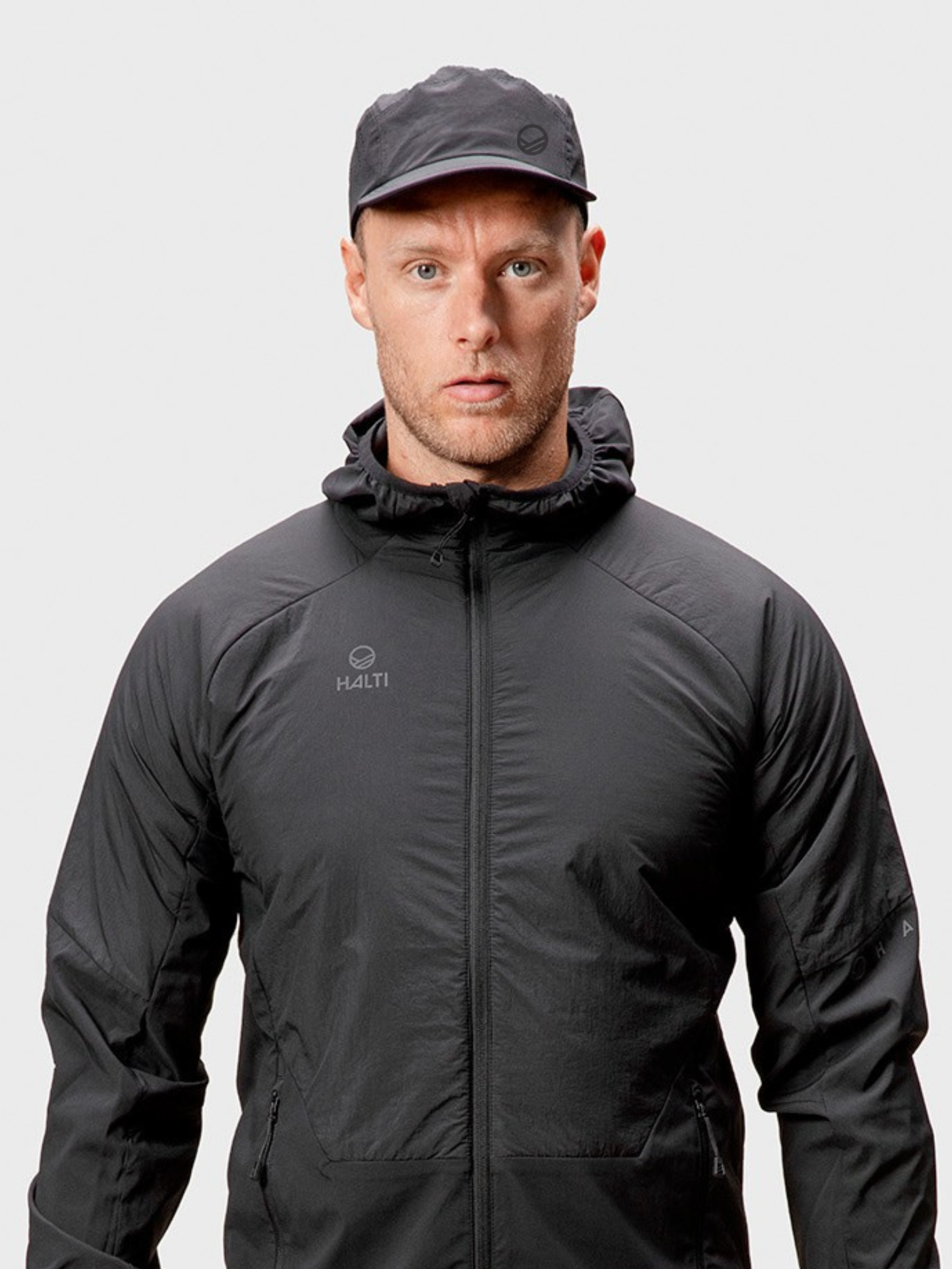 A man in a Halti Aero II Cap and black hooded jacket, facing forward against a plain light background.