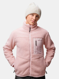 Person wears a light pink fleece jacket with a chest pocket and the Halti Huurre Beanie, hands in pockets.
