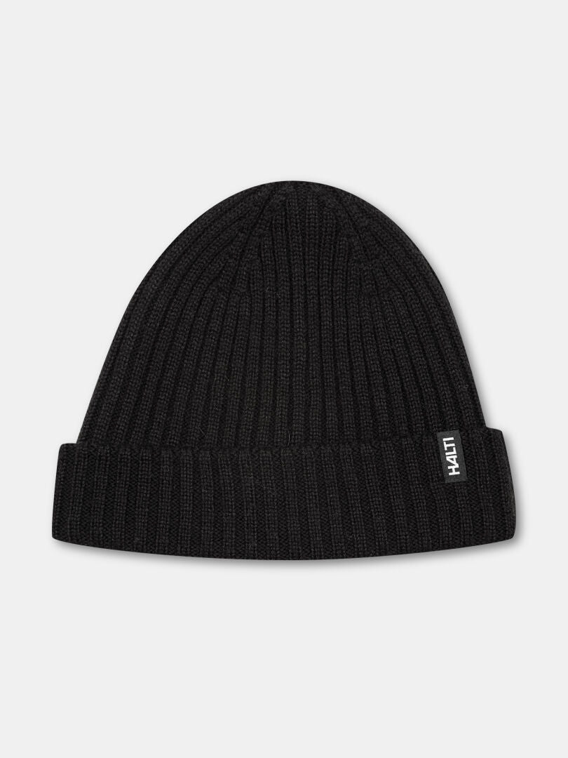Halti Runko Beanie: black rib-knit fisherman style with fold-over cuff and a small white tag on the cuff.
